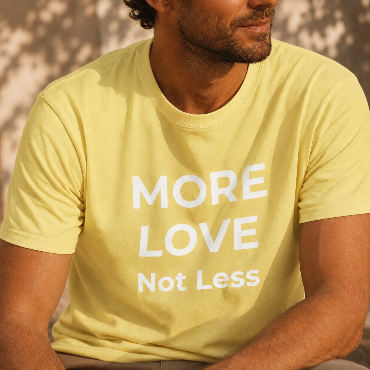 Person wearing a cornsilk yellow t-shirt with 'MORE LOVE Not Less' text.