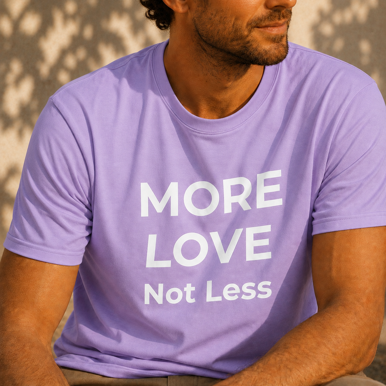Person wearing a light purple t-shirt with 'MORE LOVE Not Less' text.