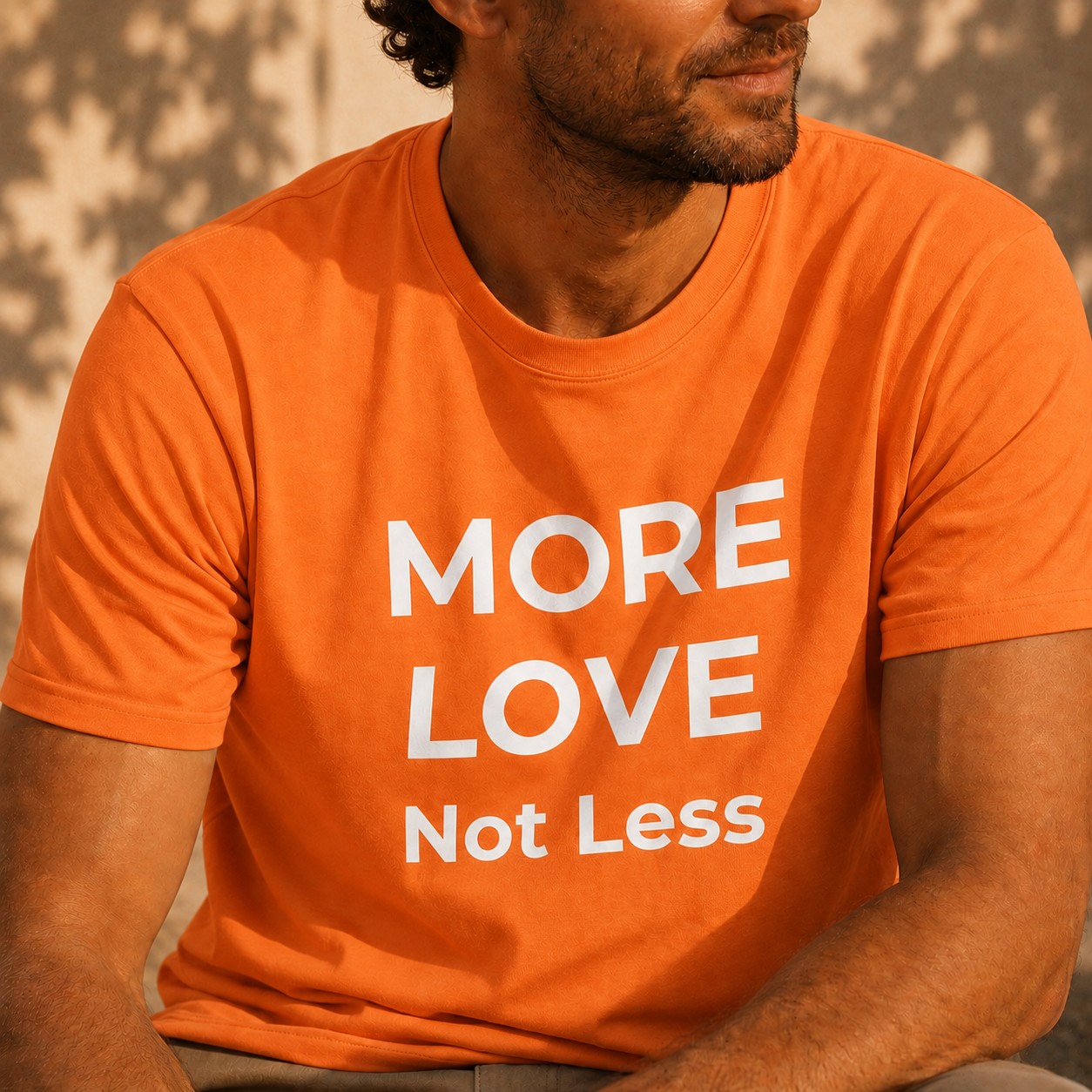 Person wearing an orange t-shirt with 'MORE LOVE Not Less' text.